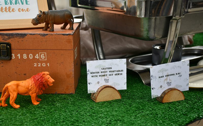 Jungle-themed buffet signage and creative wood-cut menu holders.