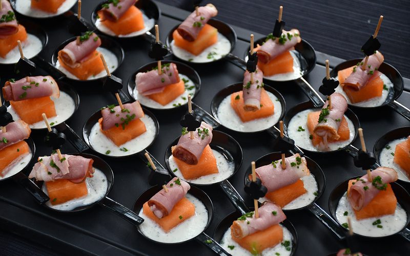 Close-up of elegant canapés with melon and ham for events.