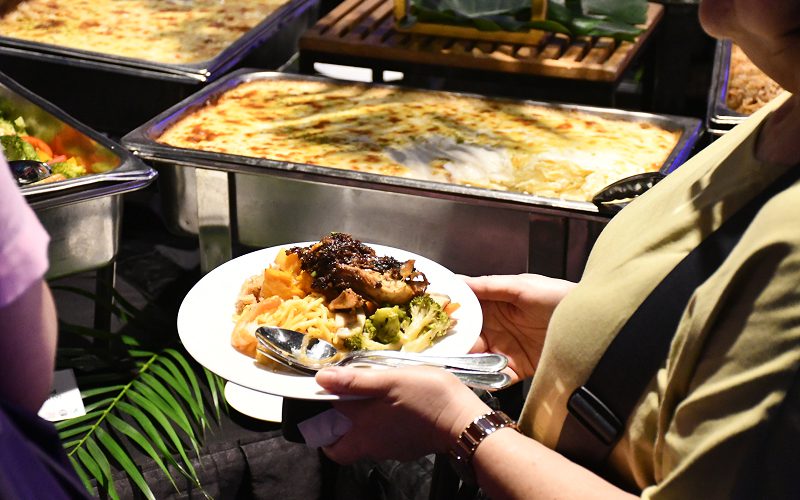 Guest holding a plate of food from a buffet selection.