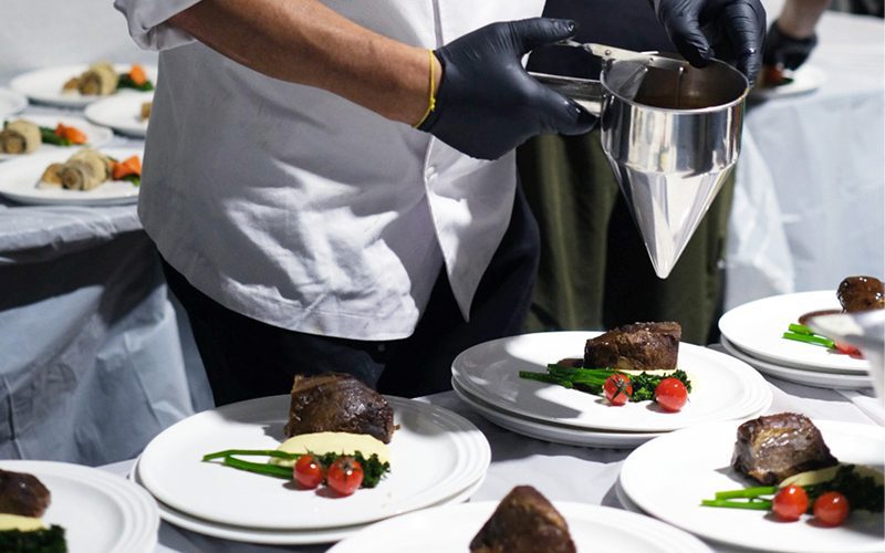 Professional catering staff plating premium beef for an event.