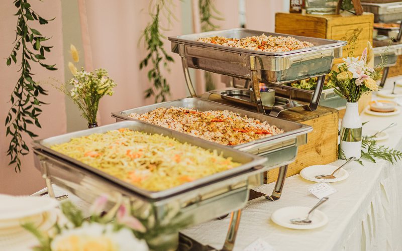 Buffet warmer trays with food prepared under catering regulations.