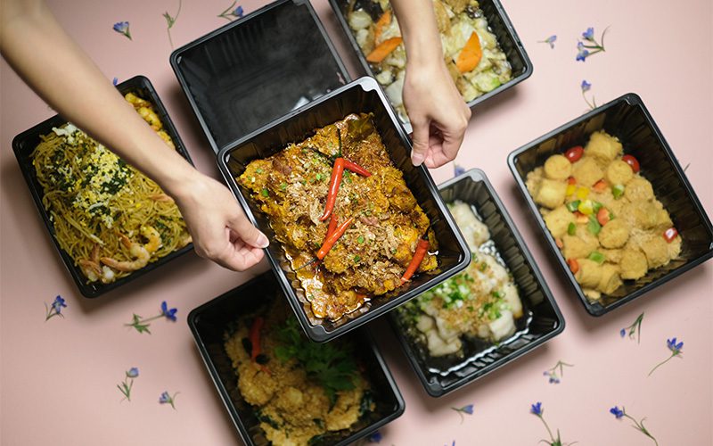 Hands holding Elsie Kitchen mini buffet bento catering boxes. 
